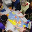 Fourth and fifth grade students from Captain Albert School in Belfast crowd around a geopolitical map of World War II following a presentation at the school by Belfast Museum and Historical Society Director Megan Pinette, top, center. (Photo by Ethan Andrews)