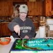 President Tammy Steinmetz cuts the Fish and Game Association’s 100th birthday cake at the clubhouse on Wiley Pond. The cake featured Wiley Pond, a fishermen with hooked fish, as well as an eagle, beaver, snapping turtle, duck and river otter. SUE MELLO/Boothbay Register