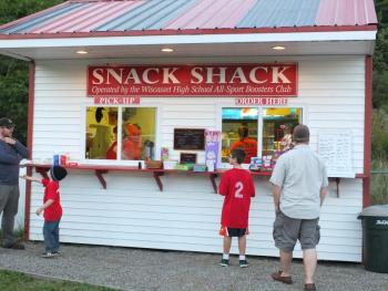 The young visitor on the left holds his hand out to is dad for money to spend at the Snack Shack operated by the Wiscasset High School All-Sports Boosters Club. KATHY ONORATO/Wiscasset Newspaper 