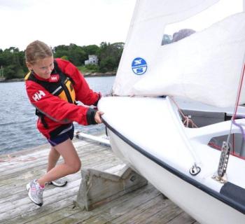 Madison Gaudette pushes in her 420 with the help of her skipper Jessica Murphy (not pictured). The Boothbay Harbor Yacht Club's Andy Holmes and Boothbay Region High School Club Sailing Team Head Coach Sally Lloyd said they would like to see the club affiliated with the high school. BEN BULKELEY/Boothbay Register