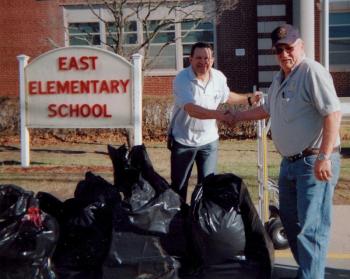 Daren Graves, right, is greeted by a school employee after dropping off items at the East Elementary School at Long Beach on Long Island, N.Y.