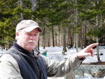 Mike Warren points out spots on the ice off the Penny Lake Bridge where his new 8-week old puppy chased wood ducks last week. KATRINA CLARK/Boothbay Register