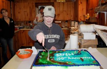 President Tammy Steinmetz cuts the Fish and Game Association’s 100th birthday cake at the clubhouse on Wiley Pond. The cake featured Wiley Pond, a fishermen with hooked fish, as well as an eagle, beaver, snapping turtle, duck and river otter. SUE MELLO/Boothbay Register