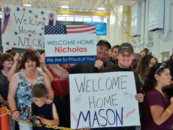 The Greenleaf and Leighton families hold signs welcoming their soldiers home from Afghanistan. Courtesy of Isaac Luken