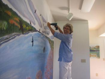 Artist Jane Dahmen hangs her contribution to the DRA's 40th anniversary art show, “Visions of the River,” which runs August 10-17 in Damariscotta. Courtesy of Damariscotta River Association