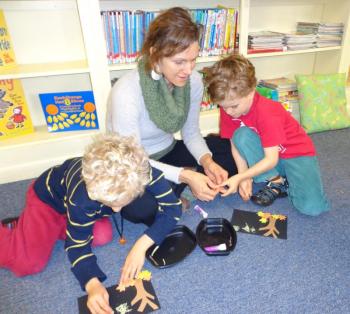 Esme Stucker and her twin sons Maddox and Tiegen collaborate on their picture during a recent Story Time.