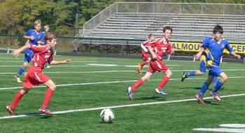 Avery Stewart (left, in red uniform) moves the ball toward the Midcoast goal as Sullivan Fink (also in red) waits for his pass in U-13 action in Falmouth. Courtesy of Marcy Tilas