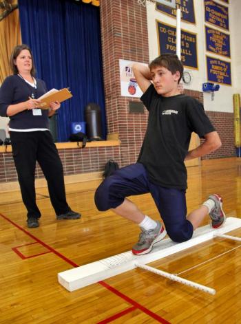 Boothbay Region High School football player Zach Blackman performs one of the movements that make up functional movement screening as LincolnHealth Physical Therapist Heather Brewer watches. The screening is designed to help pinpoint areas of weakness or vulnerability so athletes can avoid injury and perform better. Courtesy of Alan Crowell