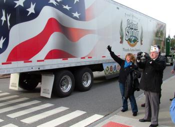 Maine First Lady Ann LePage waves to drivers from Wreaths Across America as they arrive in Belfast, Dec. 8. Next to LePage, American Legion Vice Commander Ronald Rainfrette snaps a photo. (Photo by Ethan Andrews)