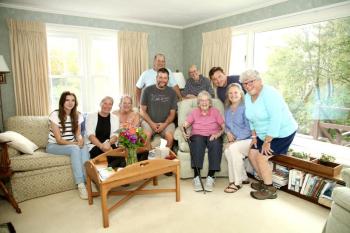 Evelyn Luther Pratt Sherman holds the Boston Post Cane surrounded by her family — Kali Andrews, Cory Chase, Anne Thompson Maher (cousin), Jack Sherman (grandson), Jerry McGrail (son-in-law), Mary Lou Thompson Koskela (cousin), Jake Brewer (grandson), Sarah Sherman (daughter), and Susan Jellison (daughter). Robert Mitchell photo