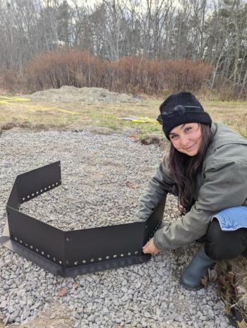 Program Manager Misha Barker sets up a firepit for BRES's new outdoor classroom. Courtesy of Erin Quinley