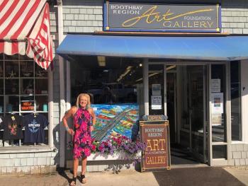 Sandra Chase Morrissey stands in front of her painting in a window at BRAF in 2022. FB photo