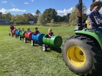 Children took a barrel ride as a tractor pulls them.