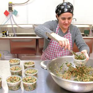 Julie Romano, of Julie Ann's Outrageous! Foods, fills containers with quinoa tabouli in the commercial kitchen space she rents at Coastal Farms Food Processing. (Photo by Ethan Andrews)