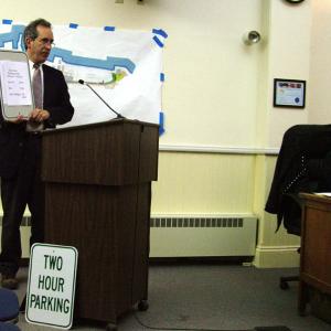 City Manager Joe Slocum shows a parking sign on which a piece of paper lists new hours for downtown, daytime parking. (Photo by Ethan Andrews)