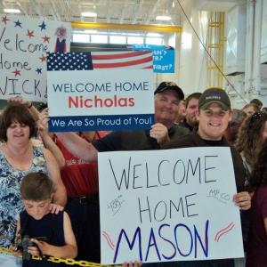 The Greenleaf and Leighton families hold signs welcoming their soldiers home from Afghanistan. Courtesy of Isaac Luken