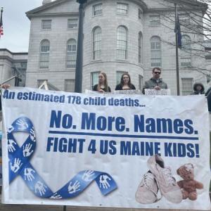 People holding a banner during a rally for child welfare system improvements.