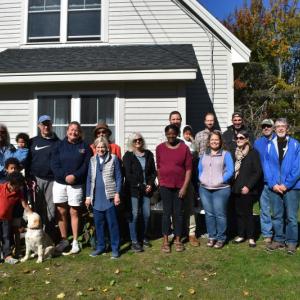 Volunteers with Midcoast Habitat for Humanity join organizers, supporters, and the selected family for a dedication ceremony, Oct. 12, 2024. (Photo by Sarah Thompson)