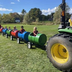 Children took a barrel ride as a tractor pulls them.