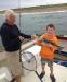 Matthew Sullivan of Boothbay Harbor shows off the striped bass he and his uncle, charter Capt. Dan Stevens, caught off the Reid State Park beach. The fish was too big to keep, so they let him go after the photo. JOE GELARDEN/Boothbay Register